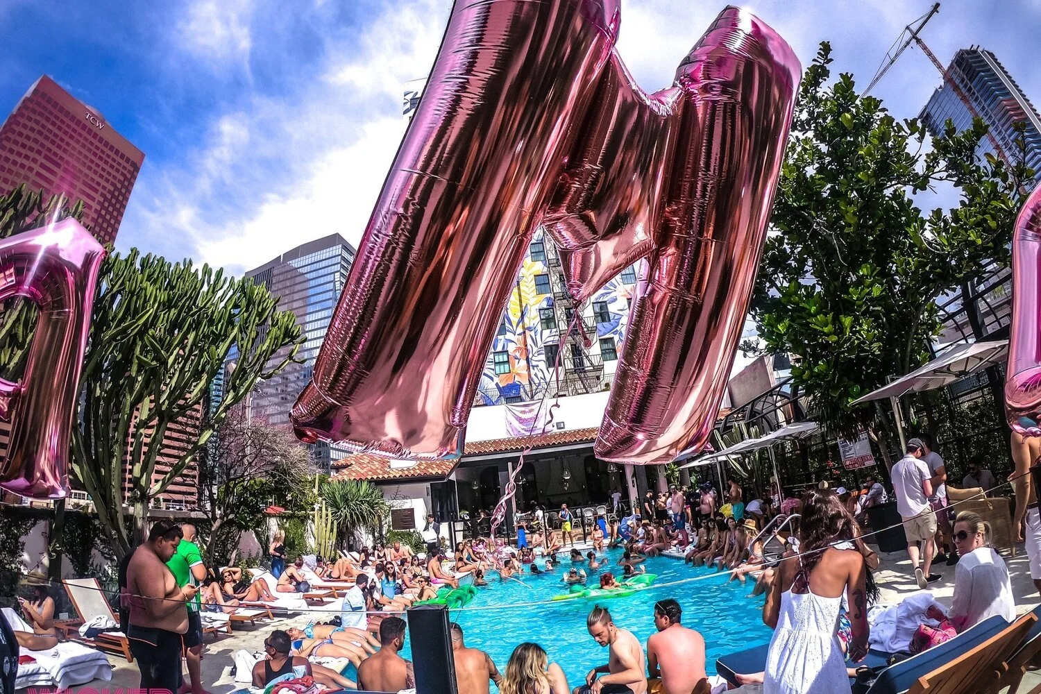Pink balloons above a Wicked Paradise pool party
